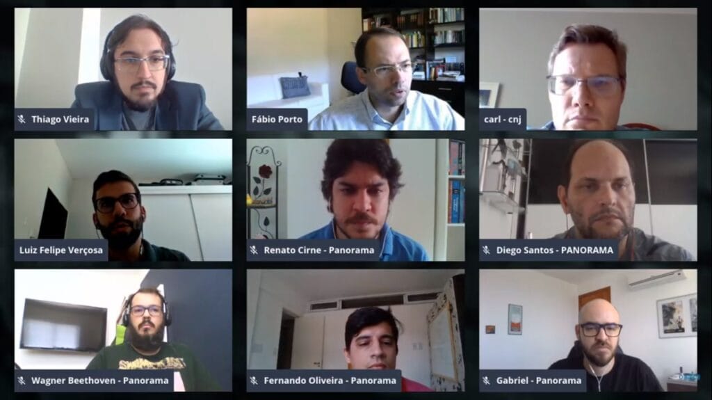 Captura de tela de uma videoconferência com nove participantes distribuídos em uma grade de três colunas e três linhas. Cada participante está em uma janela separada, e seus nomes são exibidos na parte inferior de cada janela. Os participantes estão em diferentes ambientes, alguns com fundos que mostram estantes de livros ou objetos pessoais. Entre os nomes exibidos, estão pessoas identificadas como Thiago Vieira, Fábio Porto, Carl, Luiz Felipe Verçosa, Renato Cirne, Diego Santos, Wagner Beethoven, Fernando Oliveira, e Gabriel. Todos utilizam fones de ouvido e está focada na tela.